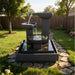 Exaco Trio Bowl tiered outdoor fountain with flowing water streams displayed in a landscaped backyard with lawn and stone pathway
