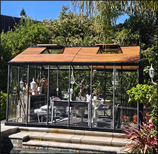 Exaco Wood Slatted Shades installed on a Victorian-style greenhouse in a backyard garden, providing shade and ventilation for plants and decor inside.