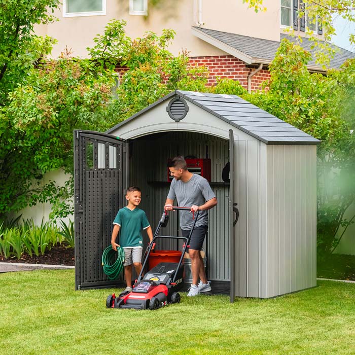 Father and son using the Lifetime Classic 8x5 Outdoor Shed for lawn care equipment storage.