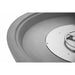 Extreme close-up, black-and-white detail shot of a concrete fire bowl's interior rim and round stainless steel burner pan, showing the layered edge profile and drilled ignition ring mounted at the center of the basin.