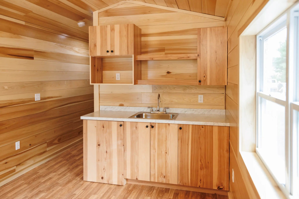 Detailed view of kitchen cabinets in the Oasis Tiny Estates Firestack Cabin, featuring natural wood and built-in storage solutions.