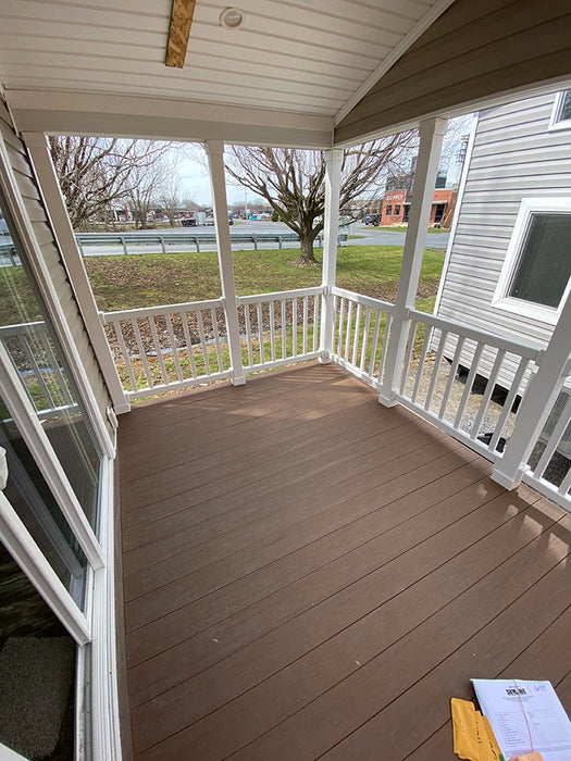 Front porch of the Champion Home No Loft by Oasis Tiny Estates, featuring wooden flooring and railings with a scenic view.