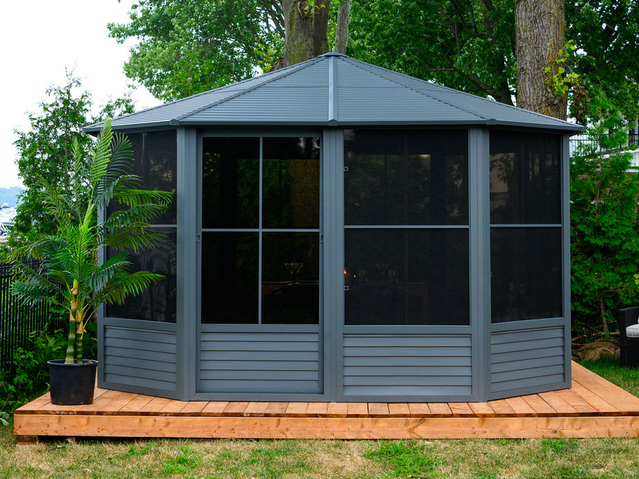Daytime view of the Gazebo with a metal roof, presenting the full exterior as it stands on a wooden deck surrounded by a lush garden.