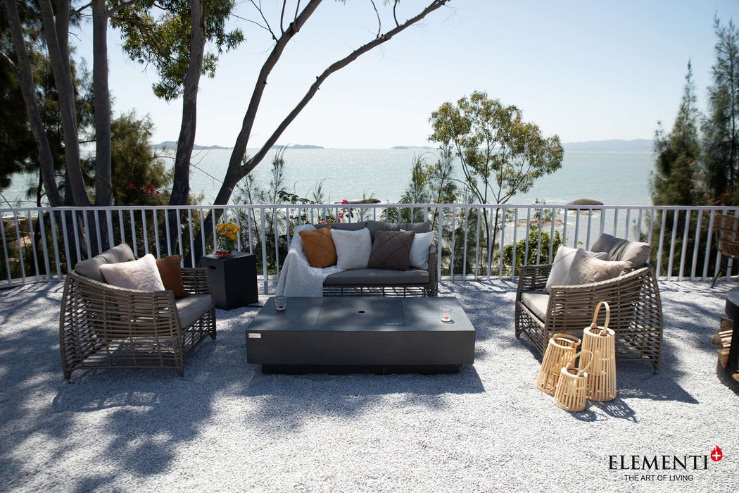 A serene patio scene showcasing wicker furniture arranged around an Elementi Cannes Fire Table for relaxation and warmth