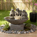 Garden frog water fountain with round textured basin and stone base, surrounded by pebbles and bamboo fence backdrop