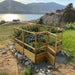 Outdoor Living Today Garden in a Box with Deer Fence 8x8 on a rock-edged hillside above a lake, cedar gate open to kale, corn and beans