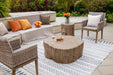 Garden patio with the Elementi Daintree red wood large coffee table, surrounded by armchairs and decorative cushions.