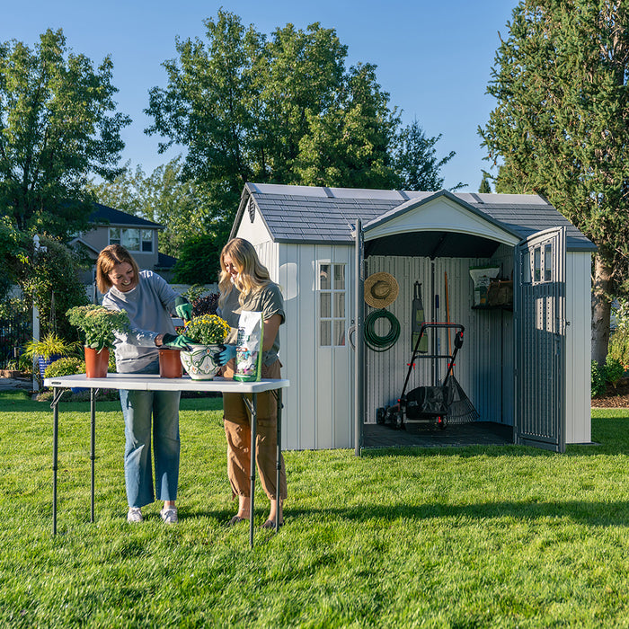  Two women gardening outside the Lifetime Shed Classic 10 x 8, featuring the shed’s open doors and spacious interior.