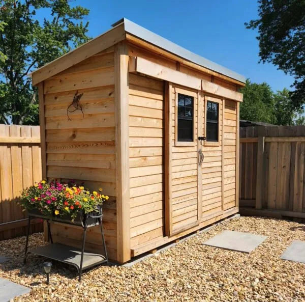 GardenSaver 12x4 Western Red Cedar Shed with sliding double doors installed on gravel base in fenced backyard setting.