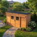 Side angle view of the Outdoor Living Today GardenSaver 12x4 shed with sliding doors, showing wood paneling and roofline.