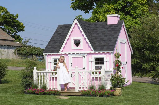 Girl playing outside the charming Victorian cottage playhouse in a garden setting.