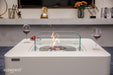 Glass guard around the burning flame of the Elementi Perth Ethanol Fire Table with red wine and snacks