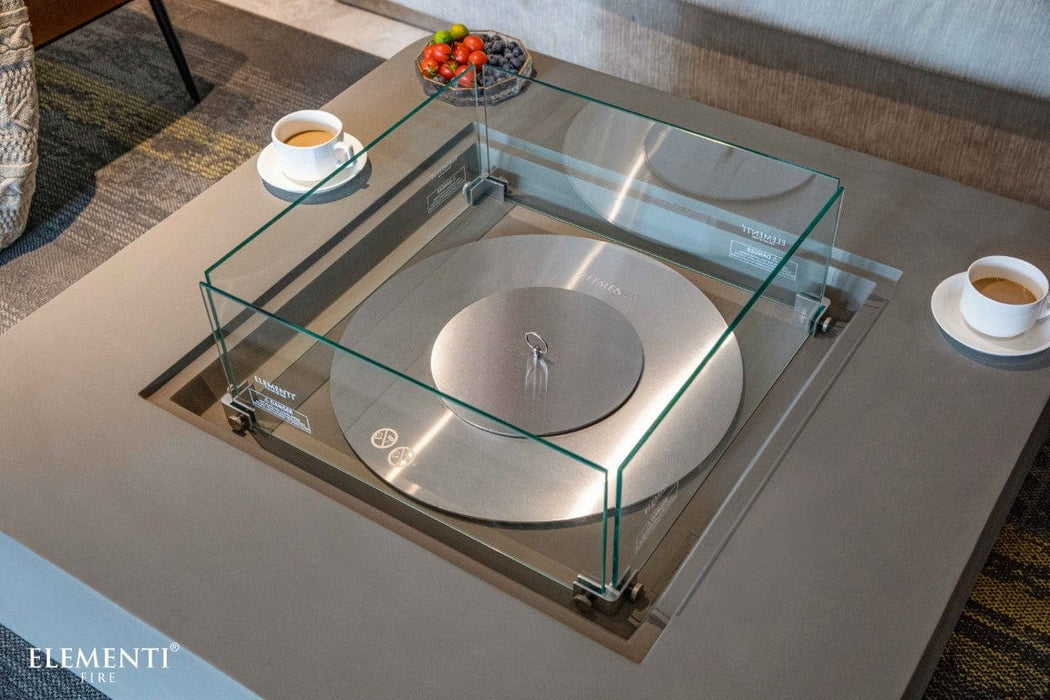 Glass top view of the Elementi Perth Fire Table in space grey, with coffee cups and fruit placed nearby