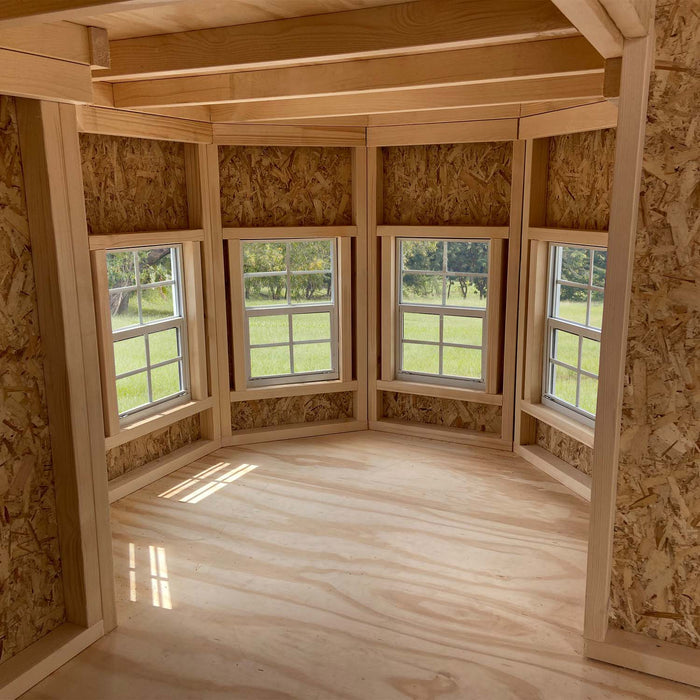 Interior bay window area of Grand Portico Mansion playhouse by Little Cottage Co., showcasing natural wood framing and bright open space