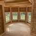 Interior bay window area of Grand Portico Mansion playhouse by Little Cottage Co., showcasing natural wood framing and bright open space