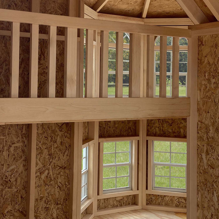 Interior view of the Little Cottage Co. Grand Portico Mansion playhouse showing loft railing, natural wood finish, and multiple bright windows