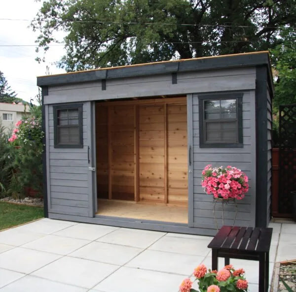 Open sliding doors of GardenSaver 12x4 cedar shed in gray finish revealing natural wood interior and patio setting.