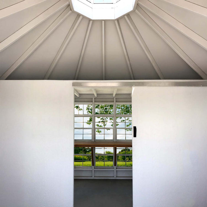 Outdoor lifestyle shot featuring the Little Cottage Co. Garden Shed Greenhouse surrounded by plants.