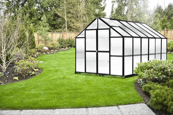 Growers Supply 12 ft greenhouse kit with black frame and translucent panels installed in landscaped backyard garden