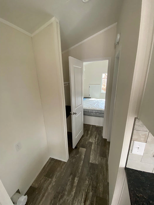 Hallway inside the Champion Home No Loft by Oasis Tiny Estates leading to various rooms, showcasing vinyl flooring.