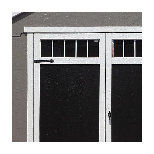 A close-up of Handy Home 10x8 Acadia double doors are black and feature glass windows on the top half in a grid pattern.