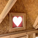 Close-up of the heart-shaped gable window inside the Little Cottage Co. Victorian Playhouse, highlighting the natural wood craftsmanship.