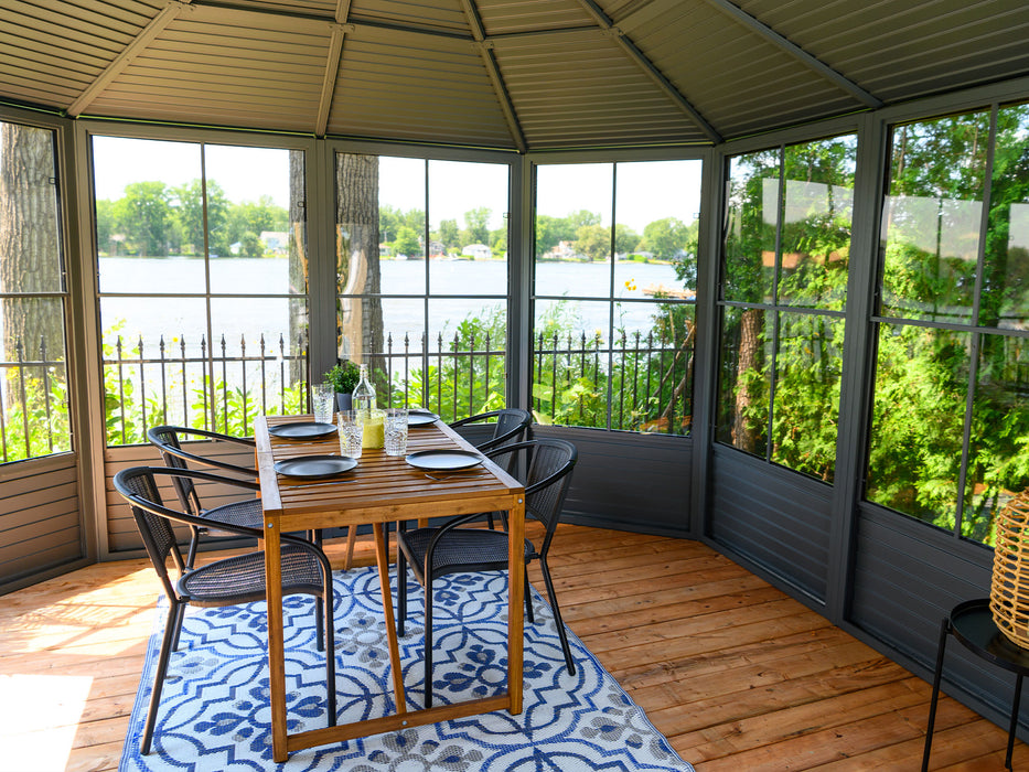 Inside view of the Florence solarium gazebo with a metal roof, showing a dining set ready for guests, with clear views of the surrounding landscape through the screened panels.