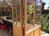 Interior of the Alton Cedar Structure Cheltenham Victorian Greenhouse featuring potted plants and a bench.