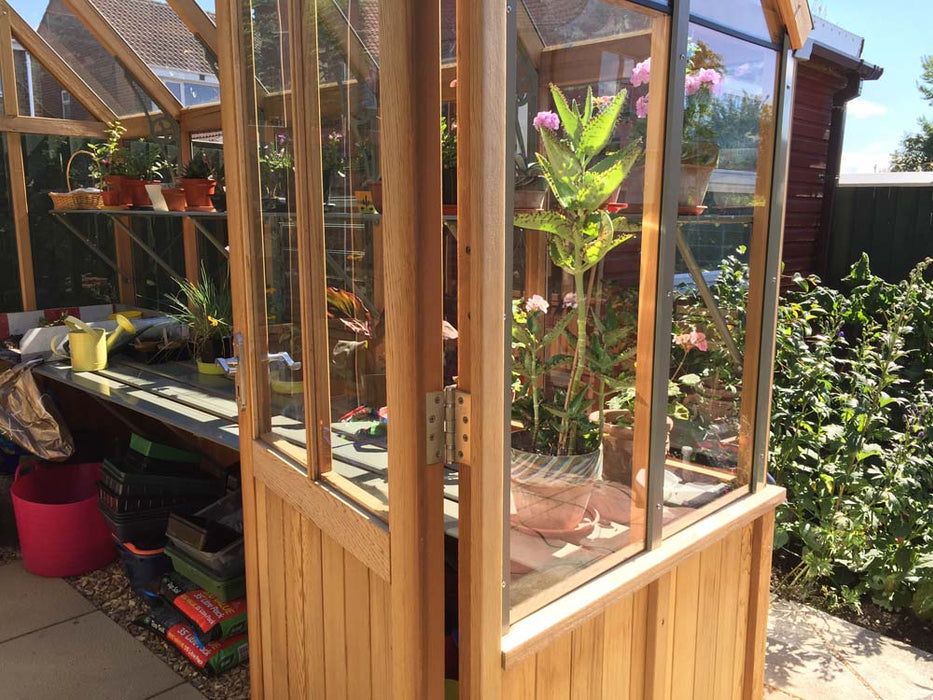 Interior of the Alton Cedar Structure Cheltenham Victorian Greenhouse featuring potted plants and a bench.