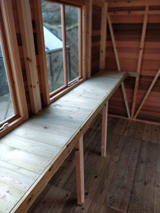 Interior view of the Alton Cedar Fusion Greenhouse showing a long wooden bench and structural wooden frame.