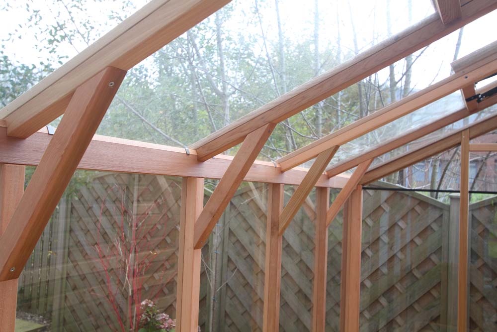 Interior view of the Alton Cedar Fusion Greenhouse showing wooden roof supports and clear glass panels.