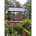 Exaco Janssens Junior Victorian Greenhouse bathed in golden sunlight, framing a tranquil garden with blooming roses.