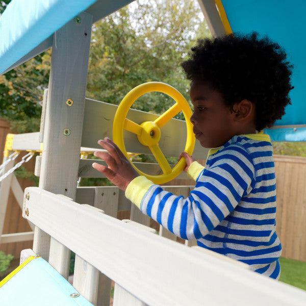 Kid playing on the steering wheel of the wooden playset