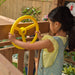 A girl playing on the yellow steering wheel of the playset