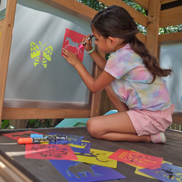 A kid painting inside the cove outdoor playhouse