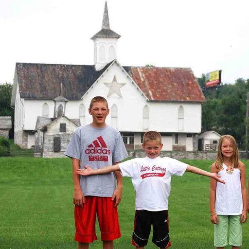 Kids smiling with the Star Barn in the background, set in a picturesque garden.