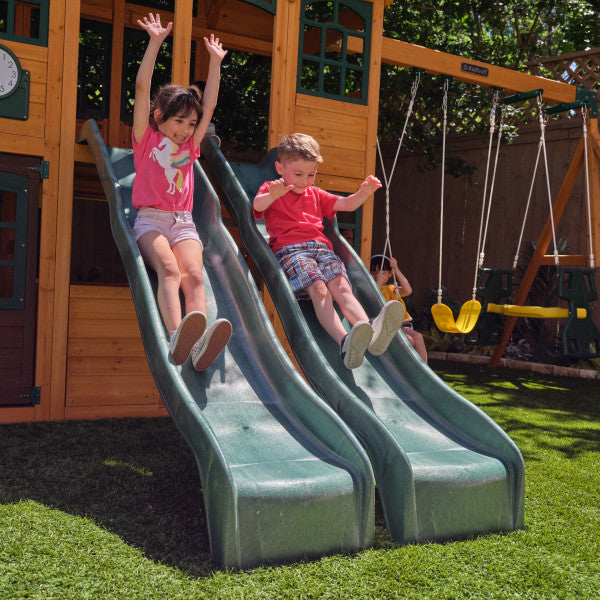 Two kids sliding on the outdoor bear cave playset