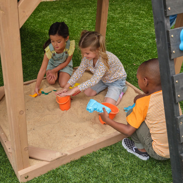 Kids playing on the sandbox of the wooden swing set