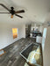 Wide-angle shot of the kitchen area inside the Champion Home No Loft, displaying the living room, kitchen, and a ceiling fan.