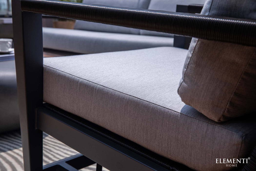 A close-up view of the comfortable, grey cushion and metal frame of an Elementi Laguna Collection outdoor chair.