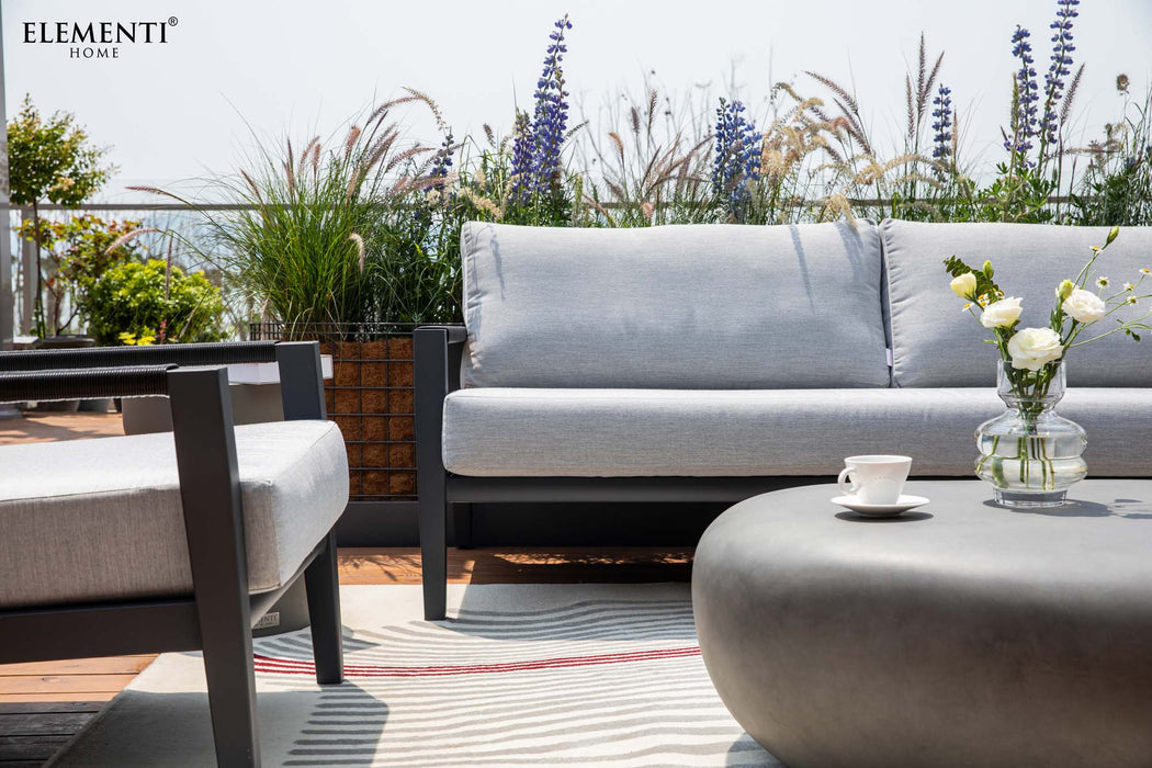A sophisticated outdoor patio set from the Elementi Laguna Collection, featuring a comfortable sofa, chair, and a central coffee table.