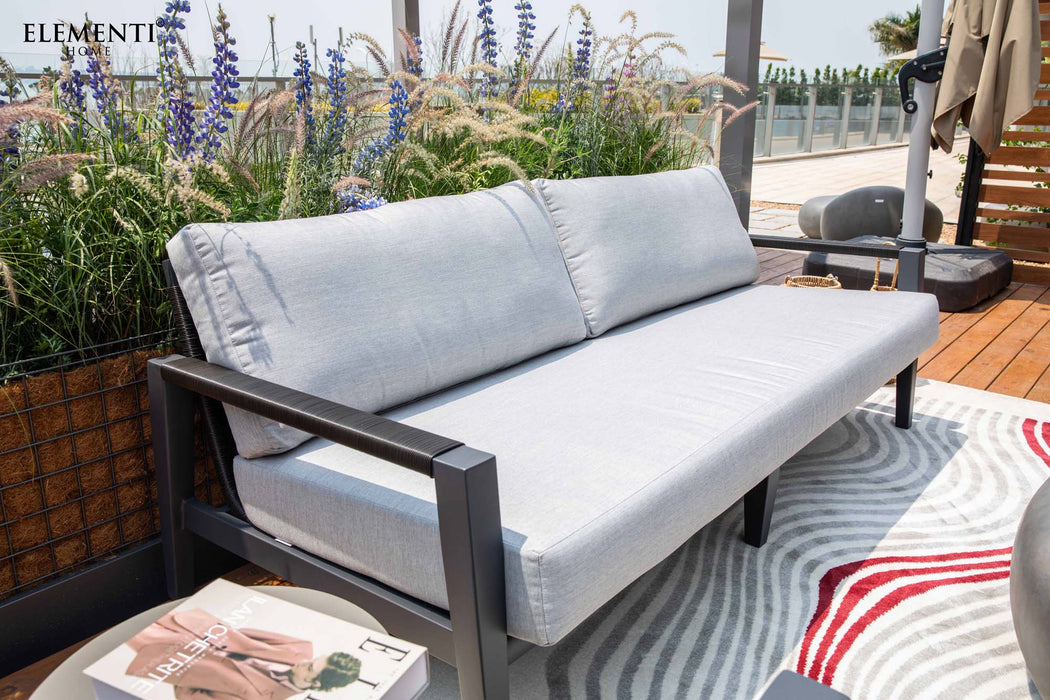 A side view of the Elementi Laguna Collection outdoor sofa, showcasing its clean lines, grey cushions, and comfortable design.