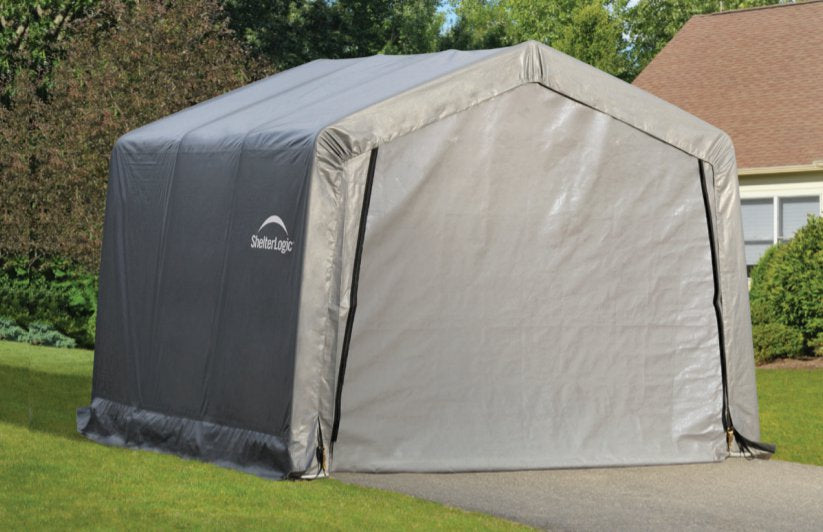 Large gray ShelterLogic peak shed set up in front of a house. This outdoor shelter provides enough space for storing lawnmowers, patio furniture, tools and more