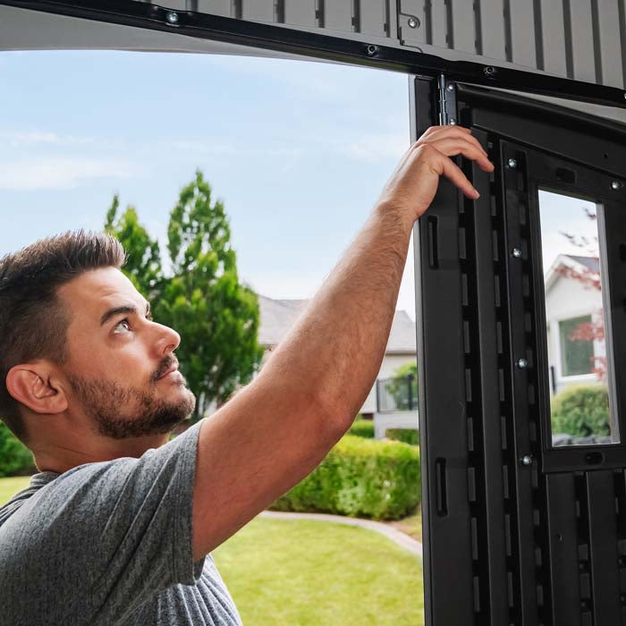 A man demonstrating the latch locking mechanism inside the Lifetime 8x5 Shed.