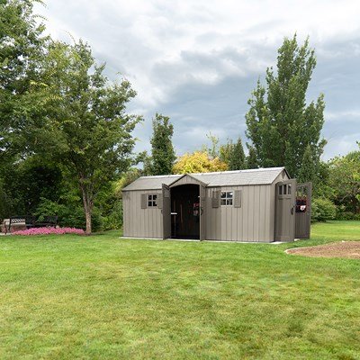 Lifetime 20x8 ft. storage shed installed in a backyard with both dual-entry doors open, flowers nearby.