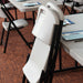 Folded Lifetime 4-Pack Classic Folding Chair in putty leaning against table with black steel frame in meeting room