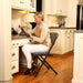 Woman seated on Lifetime 4 Pack Padded Folding Chair in kitchen workspace using tablet at built in desk.