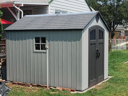 Lifetime 8x10 ft. storage shed installed on a concrete pad, front angle view with closed double doors.