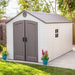 Lifetime 8x15 ft. storage shed shown from the front angle in a backyard with flowers, closed double doors.