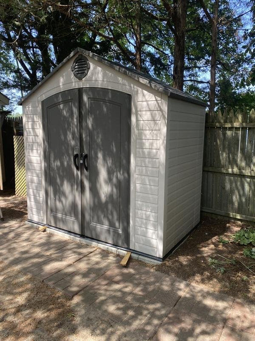 Lifetime 8x5 ft. storage shed installed on a shaded patio, front angle view with closed double doors.